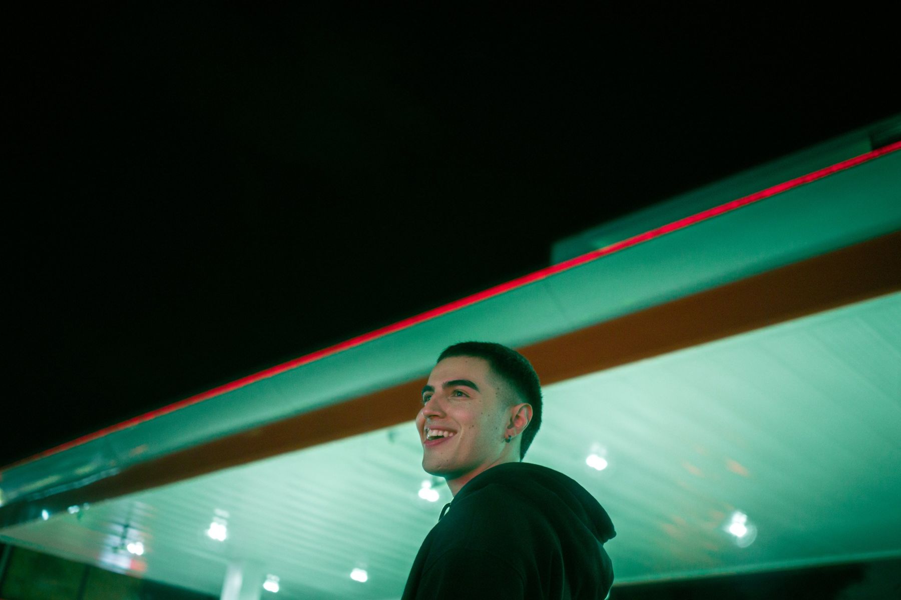 David Ospina sonriendo bajo las luces de una estación de servicio